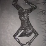 schwarze Figur, auf schwarzer Wand hängend