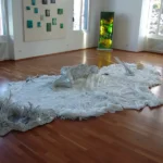 weiße Fläche mit weißen Kunststoffobjekten , Leuchtkasten in Grün im Hintergrund