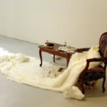 Installation mit Tisch , Stuhl, Kunstfell und kleinen Objekten